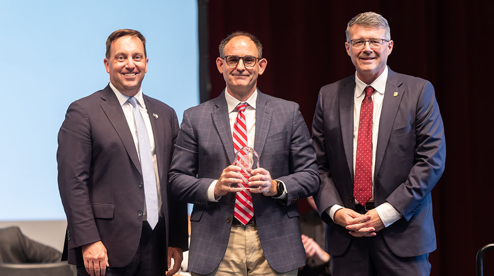 Mike Hewitt stands with President Mark C. Reed and Provost Douglas W. Woods Mike Hewitt stands with President Mark C. Reed and Provost Douglas W. Woods